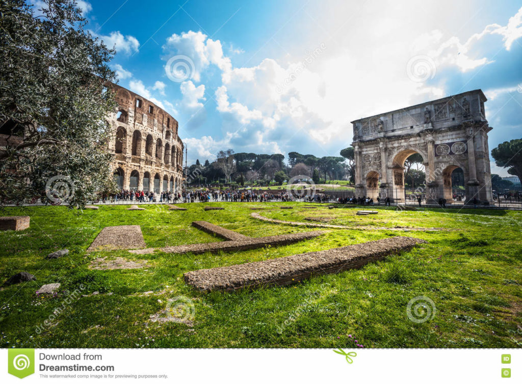 Rome, Italy. Colosseum and the Arch of Constantine Historic monuments of Rome. Imperial holes with Flavian Amphitheatre and Constantine Arch. Colosseum and the triumphal arch in the center of the Italian capital. Blue sky with some clouds. Tourists visiting.