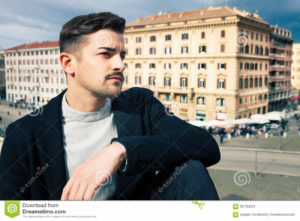 City handsome man, fashion modern hair A handsome boy looking, stylish hair and modern clothes. Horizontal portrait behind him some historic buildings in Rome, Italy. Urban scene.
