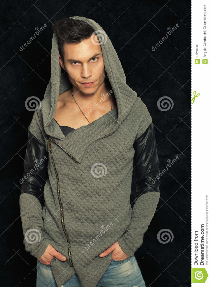 Mysterious man with hood. Portrait fashionable man Mysterious man with hood. Black grunge background. A young and mysterious man wearing a fashionable hoodie.