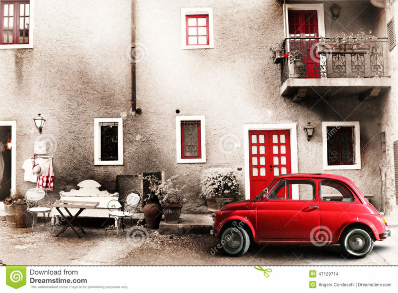 Old vintage italian scene. Small antique red car. Aging effect An old Italian with out a small subcompact old car. Vintage scene. Two chairs, a bench and a small table outside the home. A balcony with flowers and other objects of another era. Doors and windows red.