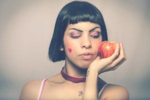 Loving nature. Young woman with apple. Young and beautiful girl with an apple in her hand. Blacks bob hair. on graduated background. Freckles and little heart on the cheek.