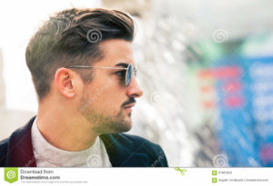 Stylish straight hair. Man profile with sunglasses. A handsome young man wearing sunglasses. Close portrait with face in profile. Space on the right for insertion of text or custom graphics. Youth trendy fashion concept. Outdoors