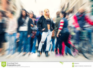 Teen blonde girl in the crowd city. Urban street city life A beautiful young blonde girl in the crowd in the city. with motion zoom blur. Casual youth clothing. Location: Rome, Italy
