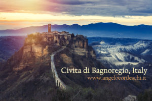 Civita di Bagnoregio, Italy. Scenery and mystical landscape of mountains. Village perched on the hill. A long bridge to reach the village. Mountain range in the background. Sunset.