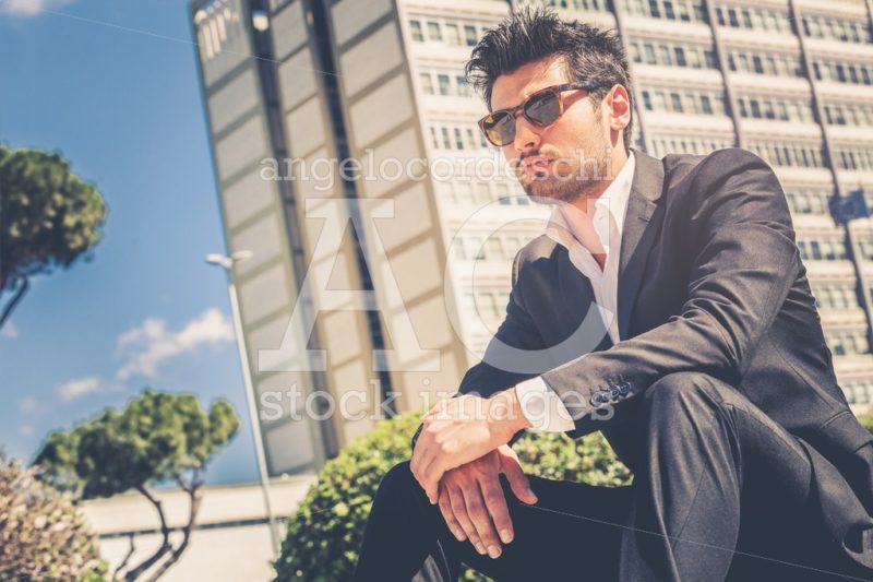 Confident handsome man with sunglasses sitting outdoor. - Angelo Cordeschi