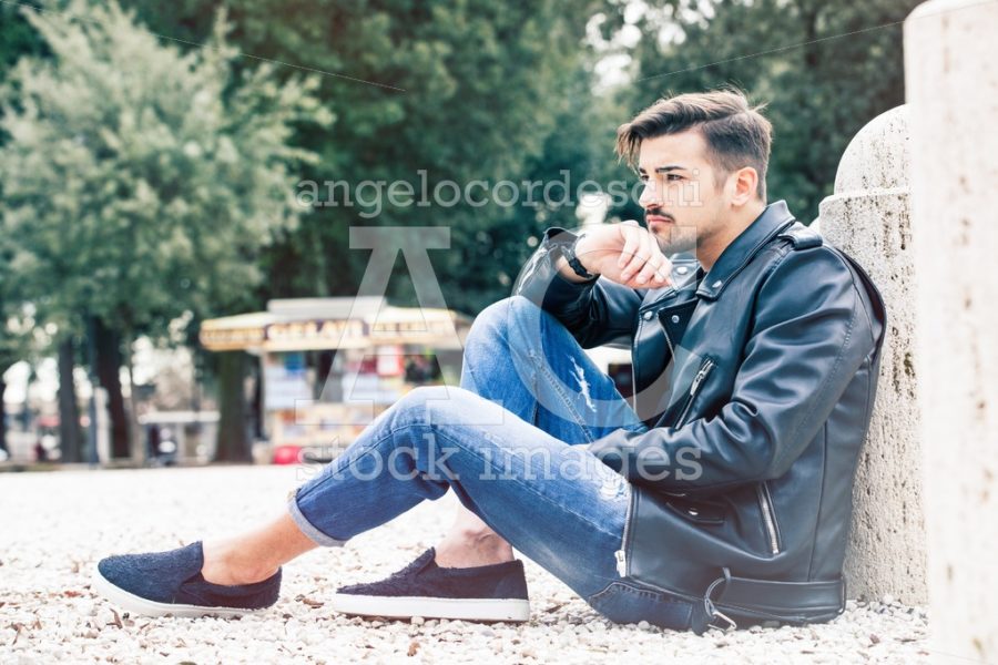 Handsome Gorgeous Young Man Sitting Outdoors. Casual Jeans And L Angelo Cordeschi