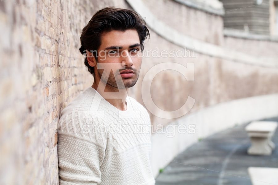 Handsome Young Man Leaning On A Long Wall Outdoors. Casual Cloth Angelo Cordeschi
