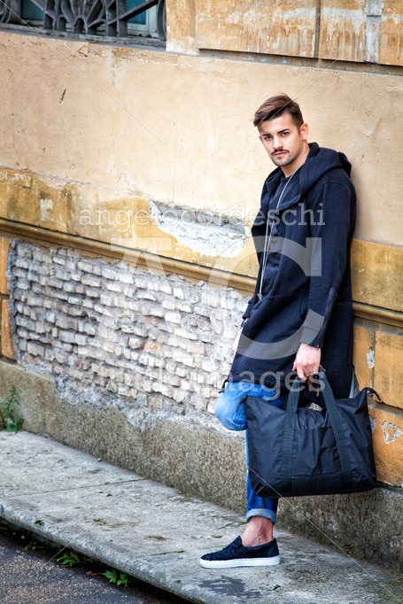 Handsome Young Man Model On The Street Leaning Against The Wall. Angelo Cordeschi