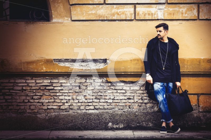 Handsome Young Man Model On The Street Leaning Against The Wall. Angelo Cordeschi