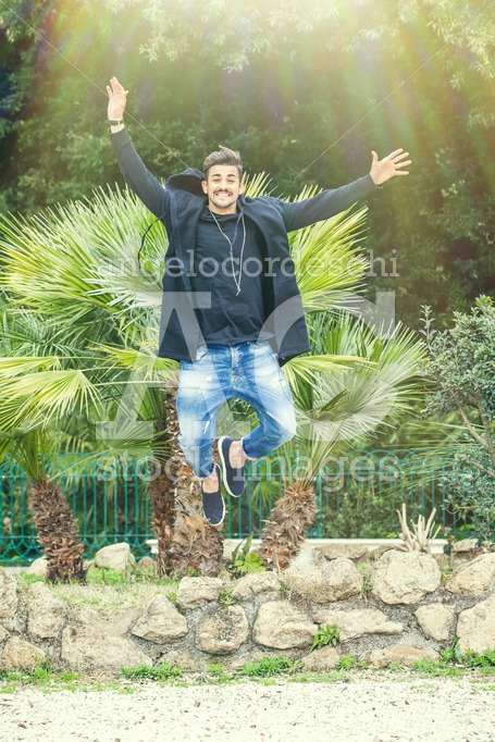 Happiness Success Of A Young Man Outdoors In A Park. Jumping For Angelo Cordeschi
