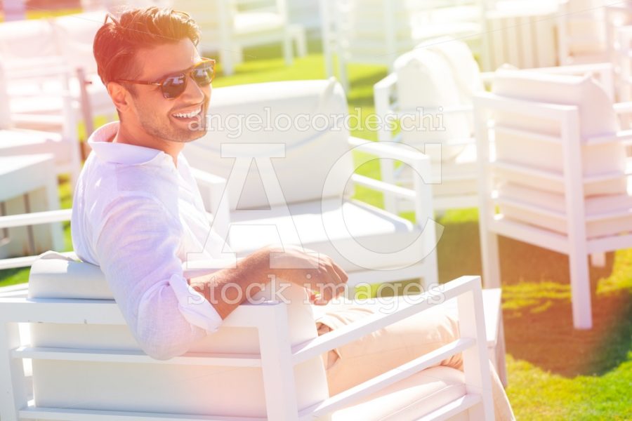 Happy And Smiling Man On Vacation Sitting In A Beach Resort With Angelo Cordeschi