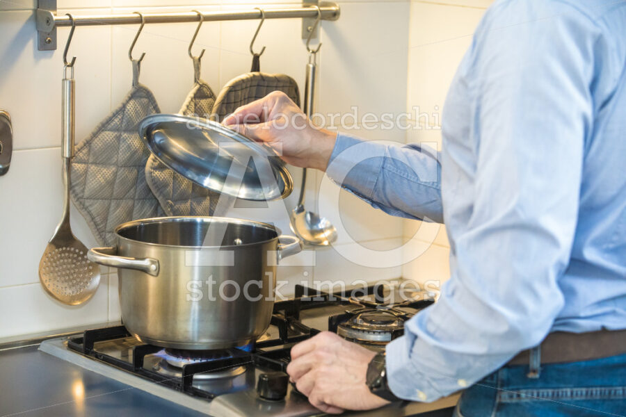 Man Cooking In The Kitchen While Lifting The Lid Of A Pot On The Angelo Cordeschi