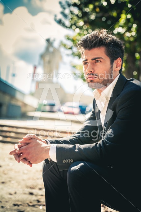Man sitting outdoors in the city on the street. Handsome style. - Angelo Cordeschi
