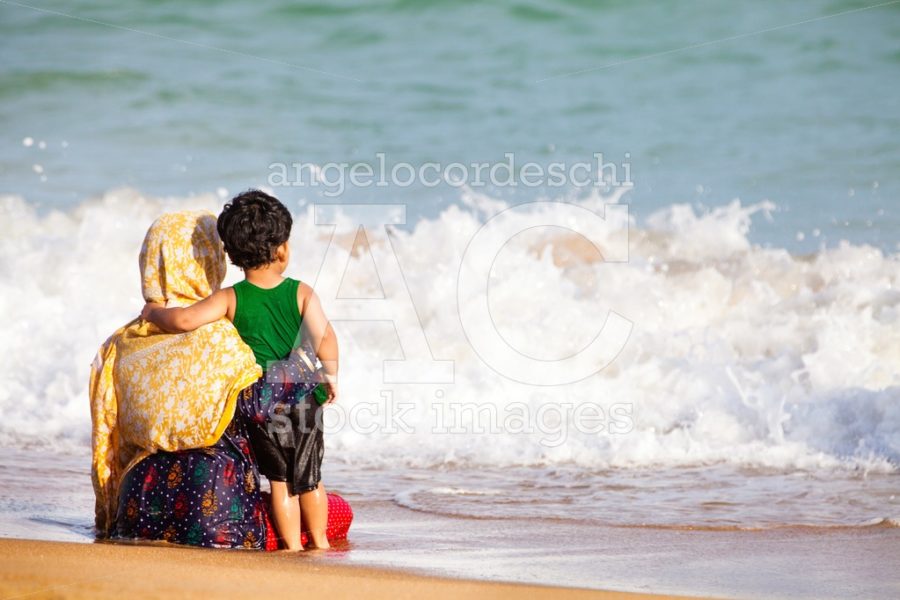 Mother And Her Little Are Sitting Embraced On The Seashore. Angelo Cordeschi