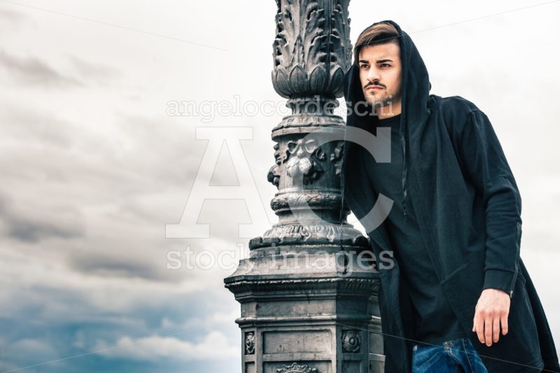 Mysterious And Handsome Young Man With Hoody Against A Lamppost. Angelo Cordeschi
