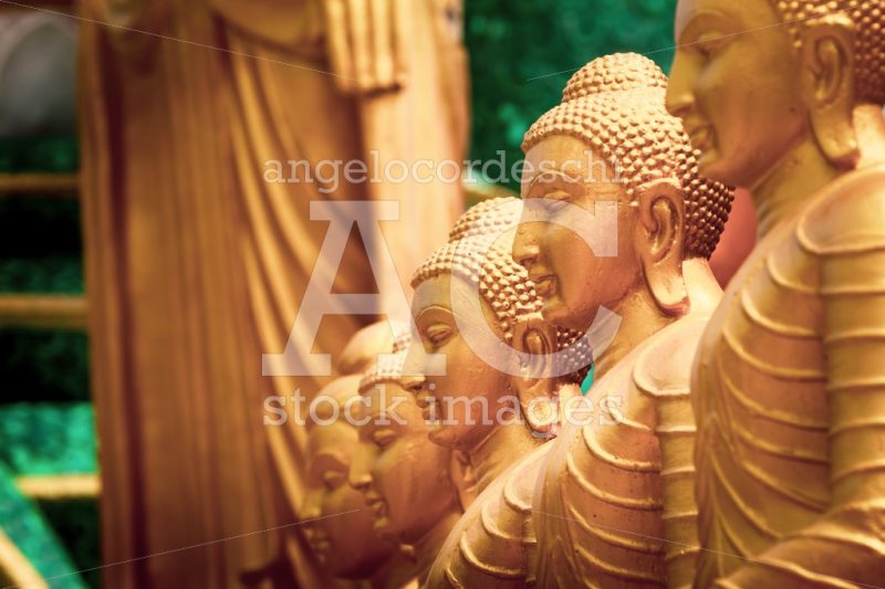 Series of Buddha statues. Face in the foreground, yellow gold sc - Angelo Cordeschi