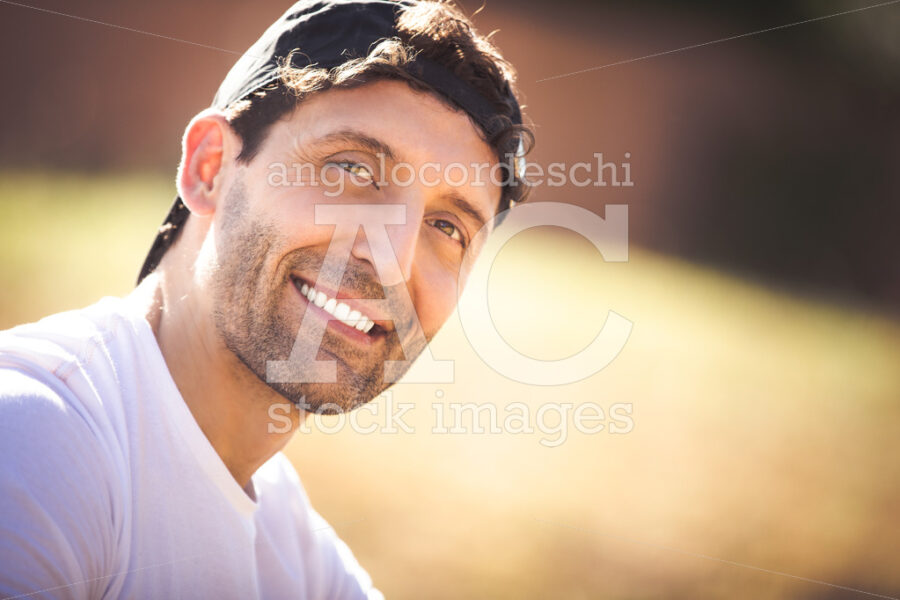 Smiling Adult Man With Hat On His Head Outdoors. Curly Hair. Angelo Cordeschi