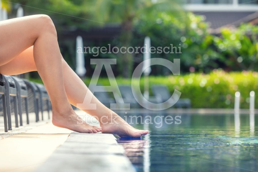 Summer Vacation In The Pool In A Resort. Woman Legs Sitting And Angelo Cordeschi