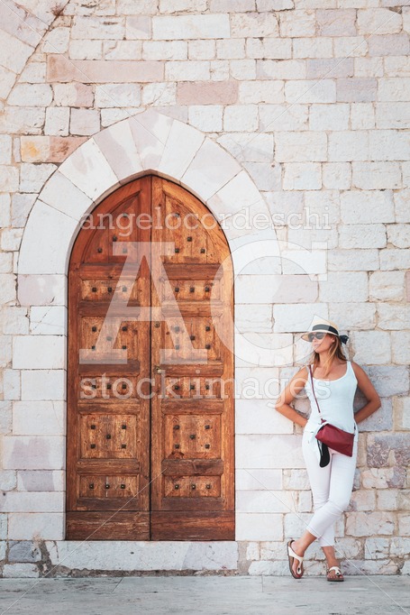 Woman Leaning On A Ancient Buildin Facade With A Historic Door. Angelo Cordeschi