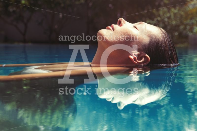 Woman relaxing and floating in swimming pool. Reflection in the - Angelo Cordeschi