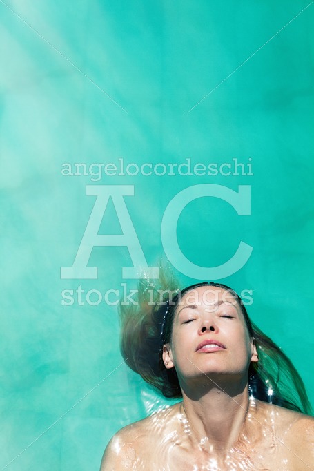 Woman relaxing floating in the pool water with closed eyes. Copy - Angelo Cordeschi