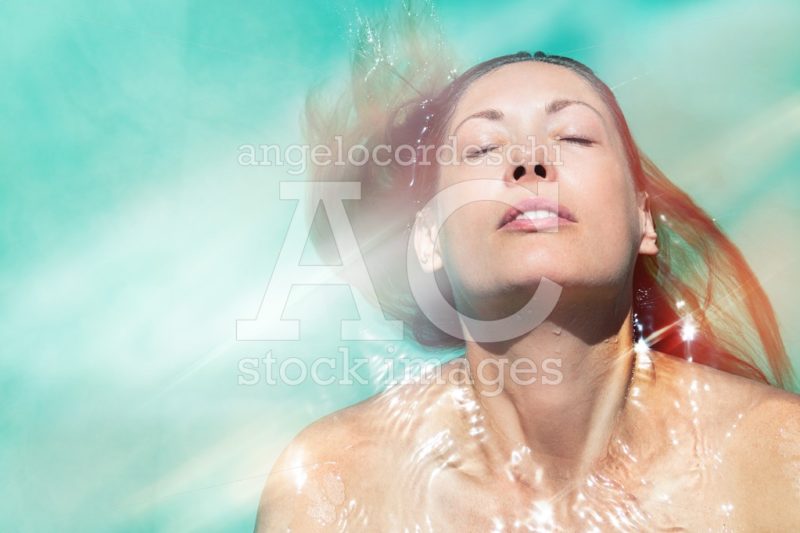Woman relaxing floating in the pool water with closed eyes. Sun - Angelo Cordeschi