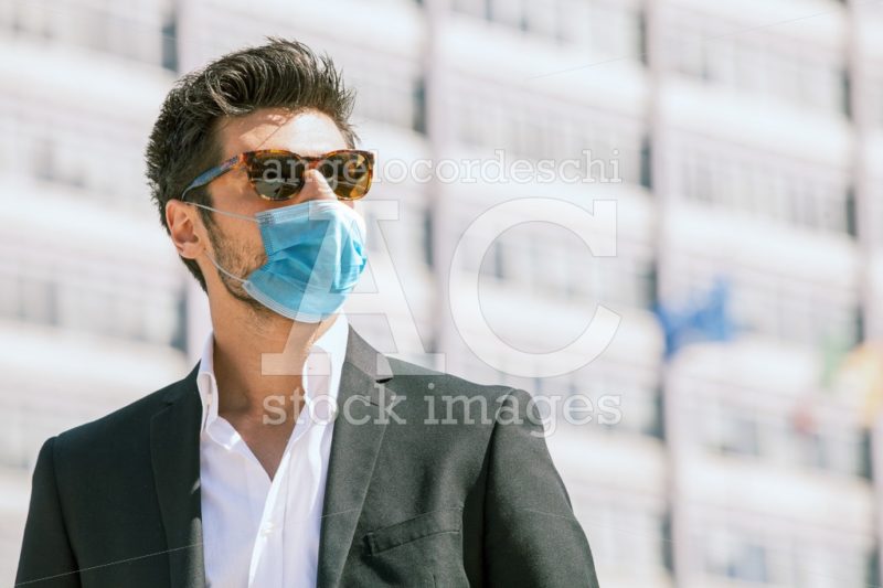 Young business man with surgical face mask and sunglasses outdoors. Coronavirus. - Angelo Cordeschi