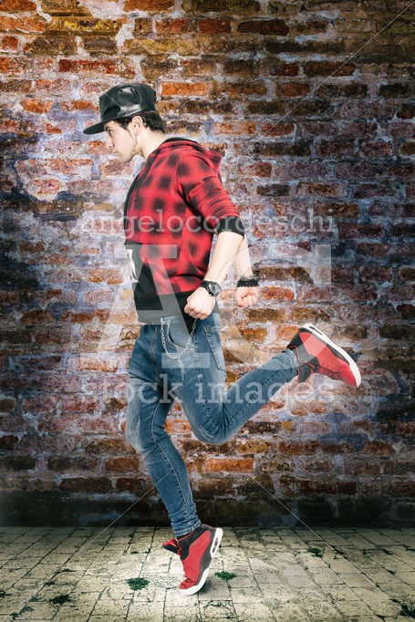 Young man dancing in front of an old brick wall and floor tiles. - Angelo Cordeschi