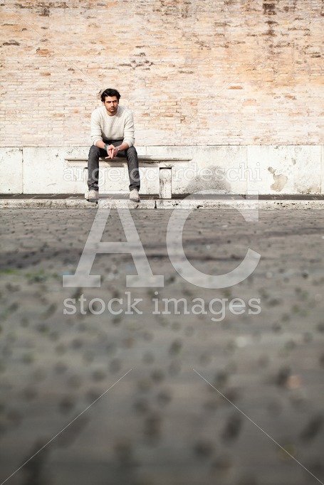 Young Man Sitting On A Marble Bench In The Street In The City. S Angelo Cordeschi